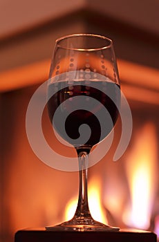 Glass with red wine in front of the fireplace