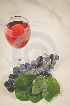 Glass of red wine and grape/glass of red wine and grape on a white marble. Selective focus