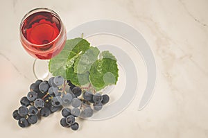 glass of red wine and grape over white/glass of red wine and grape on a white marble. Top view and copy space