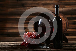 Glass of red wine with grapes on the brown wooden background