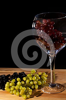 Glass of red wine grapes. Bunch of white and black grapes.