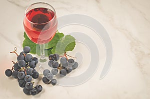 Glass of red wine and grapes/Glass of red wine and grapes on a white marble background , copy space