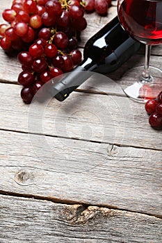 Glass of red wine with grapes on the grey wooden background