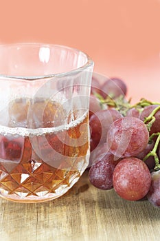 glass of red wine with grapes isolated on wooden background