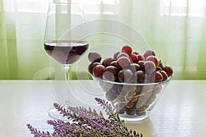 Glass of red wine, grapes and lavender on white wooden table