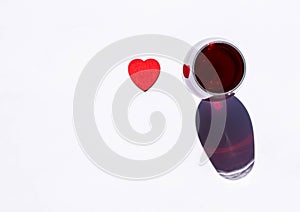 Glass of red wine with red heart and sparkling shadow on white background. Free copy space. Concept of love for good drinks,