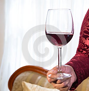 glass of red wine held by a woman& x27;s hand on white background photo