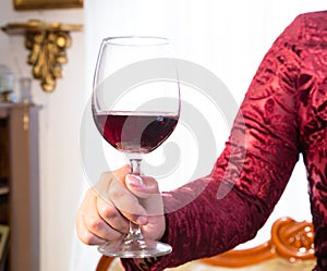 glass of red wine held by a woman& x27;s hand on white background photo