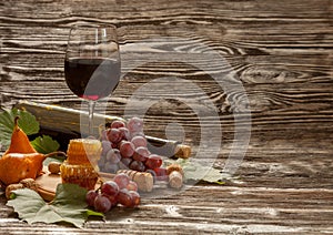 Glass of red wine, honeycomb, grapes on a wooden background.