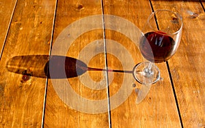 Glass of red wine and its shadow on the wooden table