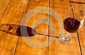 Glass of red wine and its shadow on the wooden table