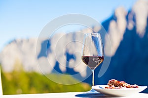 Glass of red wine and Linzer cake on a rocky mountain background. Hiking in Dolomites, Italy