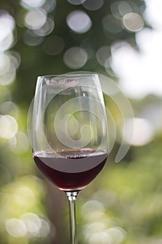 Glass of red wine with lip drying mark stain and green bokeh fro