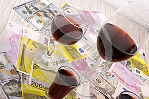 Glass of red wine and money on an old wooden table. Angle view, focus on the glass of red wine