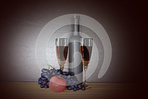 Glass of red wine near wine bottle next to apple and bunch of grapes