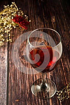 Glass of red wine over rustic, wooden textured table. Dark photo