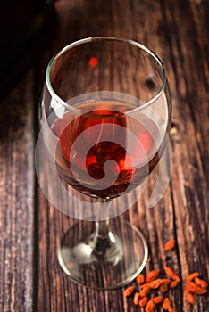 Glass of red wine over rustic, wooden textured table. Dark photo