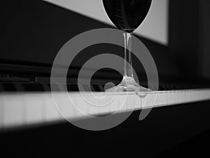 Glass of red wine on piano, black and white