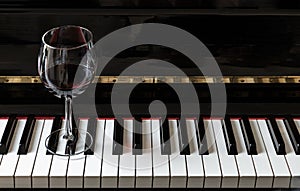 Glass of red wine on piano keyboard. Music and wine concept