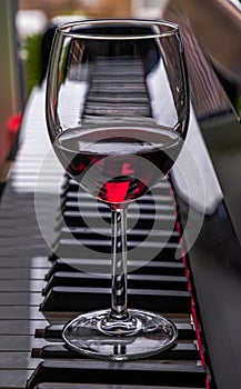 Glass of red wine on piano keyboard. Music and wine concept