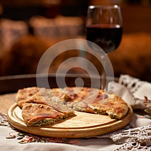 Glass of red wine and pieces of placida with cottage cheese or vertuta on a wooden tray, close-up, traditional Romanian photo