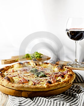 Glass of red wine with pizza on cutting board on rustic wooden table. Italian cuisine concept