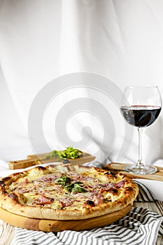 Glass of red wine with pizza on cutting board on rustic wooden table. Italian cuisine concept