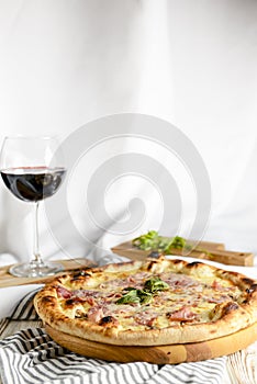 Glass of red wine with pizza on cutting board on rustic wooden table. Italian cuisine concept