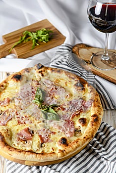 Glass of red wine with pizza on cutting board on rustic wooden table. Italian cuisine concept