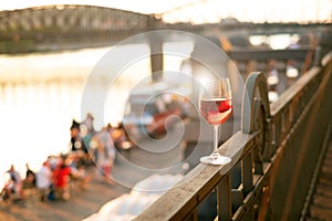 Glass of red wine on a railing with sunset in a Prague city. Concept of free time in the city and drinking alcohol.