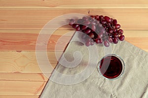 Glass red of wine and red grapes on wooden background