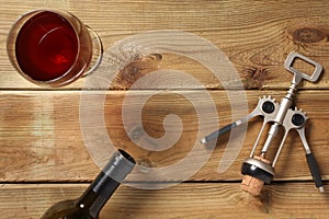 Glass of red wine, cork and a bottle on a wooden table