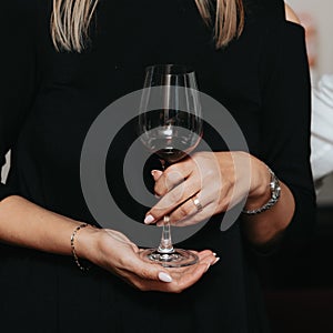 Glass of red wine seen close up in the hand at a wine tasting with friends