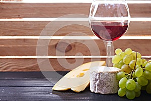 Glass of red wine, served with grapes and cheese