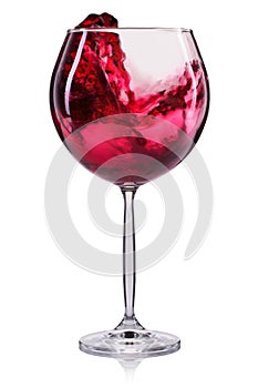 Glass of red wine with splash and drops on wineglass isolated on white background