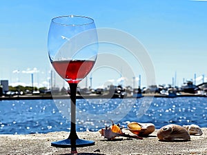 Glass of red wine on table in beach yachting club restaurant on horizon boat  in harbor seascape blue sky and seashell lifestyle