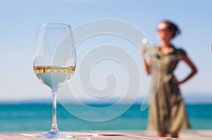 Glass of red wine on table over young woman Lazise backgound