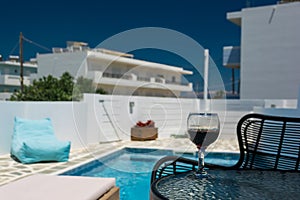 A glass of red wine on the table by the pool