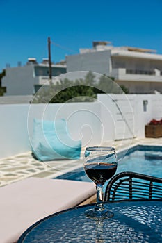 A glass of red wine on the table by the pool