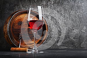 Glass with red wine for tasting and wooden barrel in dark cellar
