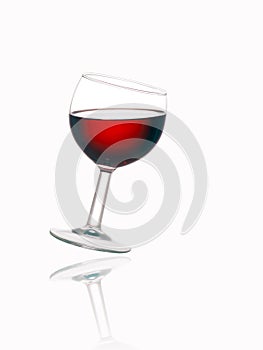 Glass of red wine, tilted, with reflection, white background.