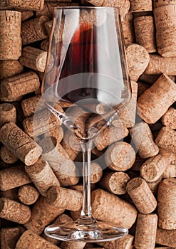 Glass of red wine on top of various wine corks