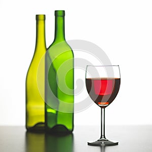 Glass of red wine with two empty bottles