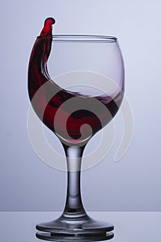 A glass of red wine with a wave. Red wine is splashed out of a glass round glass transparent glasses