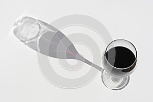 Glass of red wine on a white background with dark deep shadow