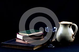 Glass of Red Wine with Wine Jug and Old Books on a Black Felt Table Cover