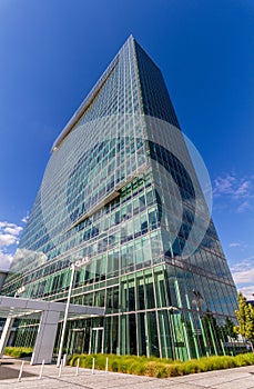 Glass reflective office buildings against blue sky with clouds and sun light