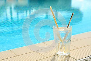 Glass of drink near swimming pool. Space for text