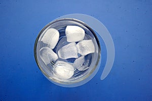 glass of refreshing ice  cube top view on blue background