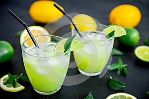 Glass of refreshing lemonade with limes, lemons and mint